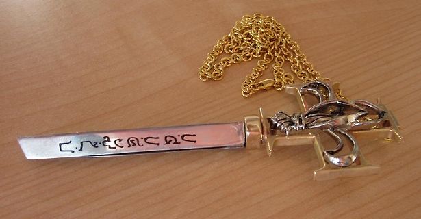 Schwertförmiger Anhänger mit Kette auf Holzuntergrund