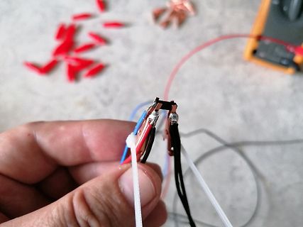 Hand hält Lötstellen mit Drähten und Kabelbindern