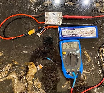 Multimeter, LiPo-Akku, Regler und Bauteile auf Tischplatte