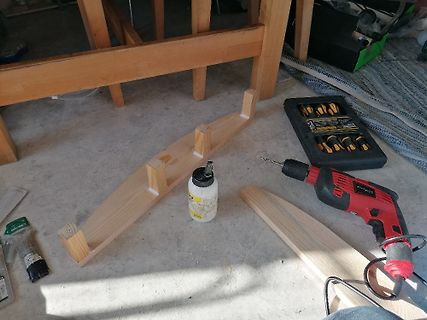 Werkzeuge und Holzbauteile auf Werkstattboden