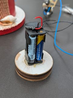 Zwei AAA-Batterien in Halterung auf Holzsockel