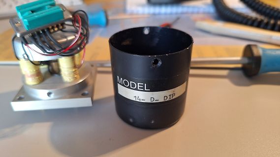 Elektronikbauteile und schwarzer Zylinder auf Werkstattunterlage