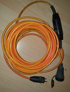 Aufgewickeltes orangefarbenes Verlängerungskabel mit Steckern