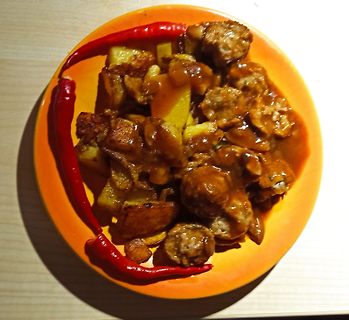 Essen mit Kartoffeln, Fleisch und roten Chilischoten