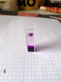Küvette mit violetter Flüssigkeit auf Karopapier