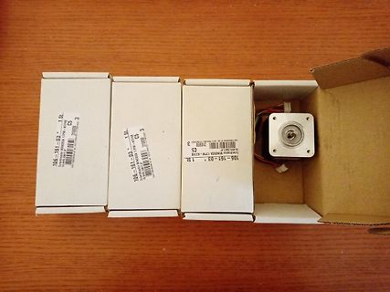 Drei Kartons und ein elektronisches Bauteil auf Holzuntergrund