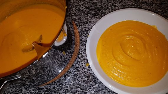 Topf und Teller mit Kürbissuppe