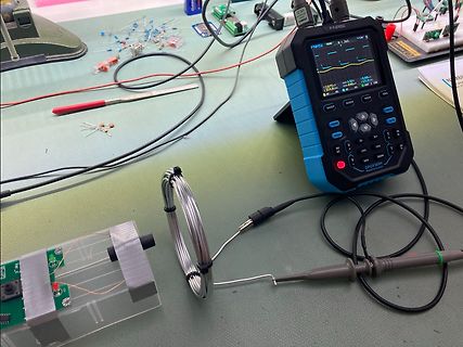 Elektronik-Messaufbau mit Handheld-Oszilloskop und Spule