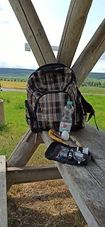 Rucksack, Wasserflasche und Proviant auf Holzbank