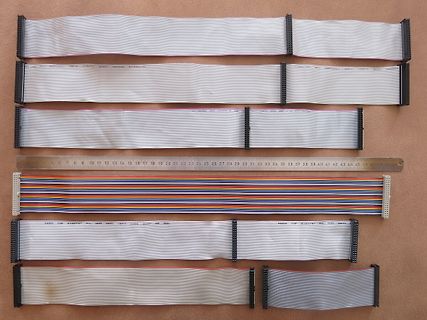 Verschiedene Flachbandkabel und ein Lineal auf Holzuntergrund