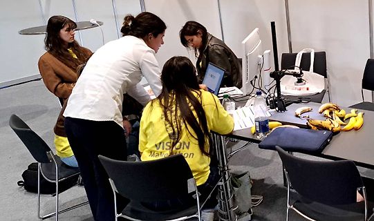 Gruppe von Personen an einem Tisch mit Laptop und Bananen
