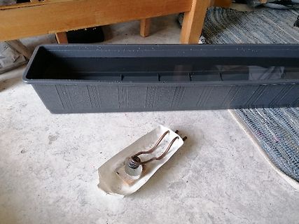 Blumenkasten und defekter Leuchtmittelhalter auf Boden