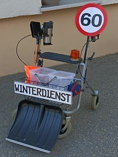 Modifizierter Rollstuhl mit Schneeschaufel und Winterdienst-Schild