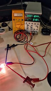 Elektronik-Messaufbau mit Netzteil, Multimeter und leuchtender LED