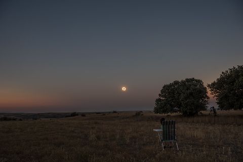 Sonnenfinsternis über einer Landschaft mit Person im Stuhl