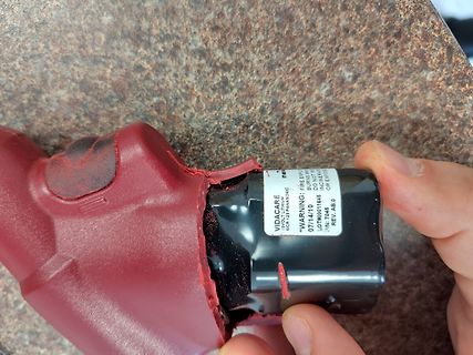 Hand hält schwarzes Bauteil in roter Hülle