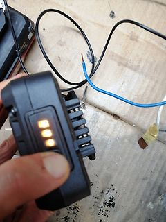 Hand hält Akku-Ladegerät mit Kabeln