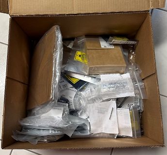 Inhalt eines Versandkartons mit verpackten Bauteilen