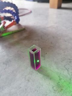 Küvette mit violetter Flüssigkeit und grünem Lichtpunkt