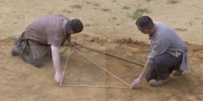 Zwei Personen markieren ein Dreieck im Sand