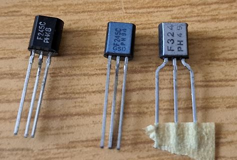 Drei elektronische Bauteile auf Holzuntergrund