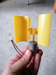 Gelber Windgenerator mit Elektromotor in Hand gehalten