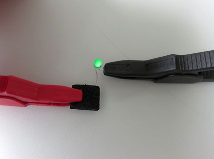 Leuchtende LED zwischen zwei Krokodilklemmen