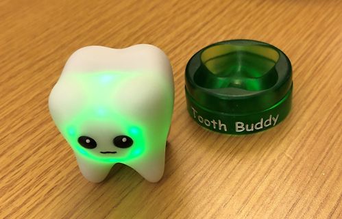 Leuchtender Zahn und grüne Dose auf Holztisch