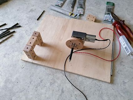 Experimenteller Aufbau mit Motor und Stift auf Holzbrett
