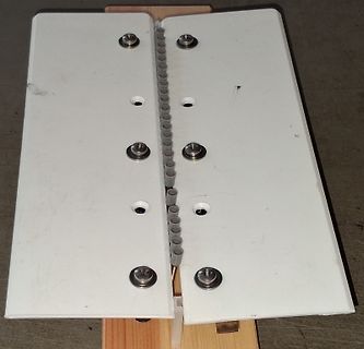 Zwei weiße Platten mit Schrauben und Zahnstangen