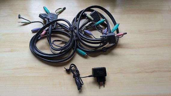 Diverse Audiokabel und ein Netzteil auf Holztisch