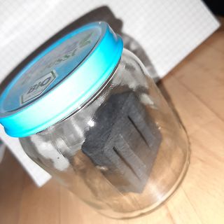 Glasgefäß mit dunklem Inhalt auf Holzuntergrund