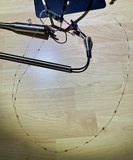 Elektronischer Aufbau mit Drahtschleife und Platine auf Holzuntergrund