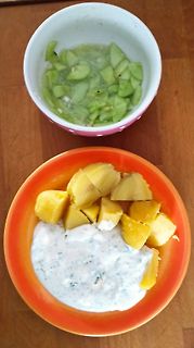 Schalen mit Gurkenstücken und gelben Früchten mit Dip