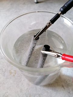 Elektrolyse von Wasser mit Krokodilklemmen in Becherglas
