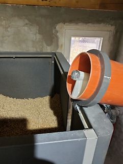 Großer orangefarbener Trichter über einem Behälter mit Spänen