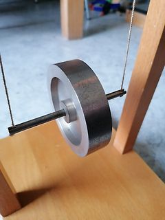 Metallisches Schwungrad an einer Achse auf Holzgestell