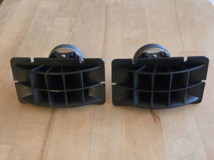 Zwei schwarze Kunststoff-Bauteile auf Holztisch