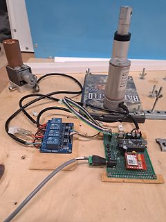 Elektronik-Aufbau mit Relaismodul und Mikrocontroller auf Holzbrett