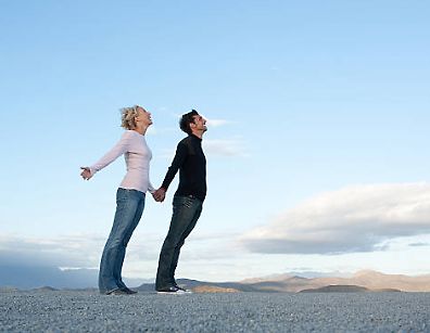 Mann und Frau halten Händchen unter freiem Himmel