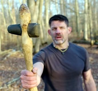 Mann hält selbstgemachten Holzhammer in den Vordergrund