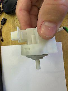 Weißes Kunststoffbauteil in einer Hand