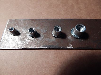Vier Gewindebuchsen auf Metallplatte