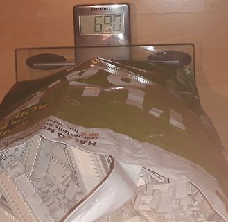 Digitale Waage mit Beutel voller weißer Bauteile
