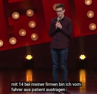 Mann auf einer Bühne mit Untertitel