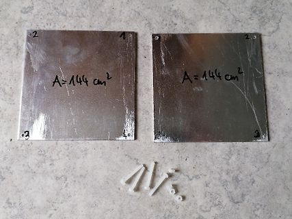 Zwei Metallplatten mit Beschriftung und kleine Kunststoffteile