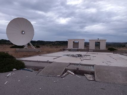 Satellitenschüssel auf Betonfundament unter bewölktem Himmel