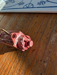 Defektes rotes Bauteil auf Holzuntergrund