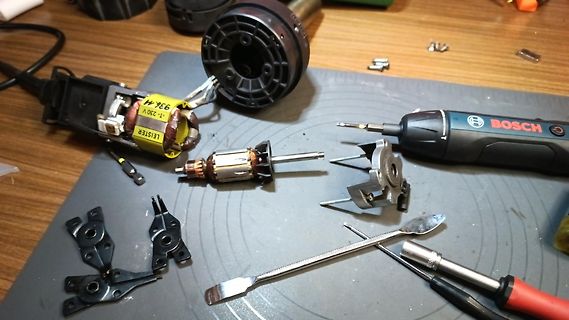 Zerlegte Elektrowerkzeug-Komponenten auf Werkstattunterlage