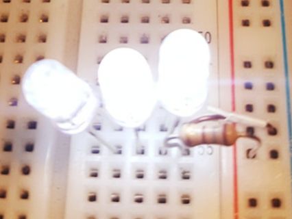 Drei leuchtende LEDs auf einem Breadboard mit Widerstand